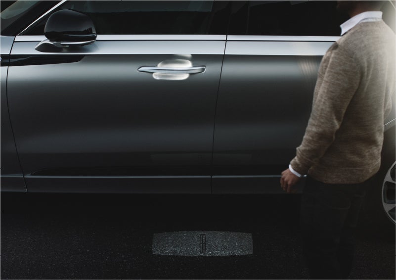 A person approaches a 2023 Lincoln Aviator® Grand Touring SUV as the Lincoln Embrace sequence of welcome lighting illuminates | Uptown Lincoln in Wauwatosa WI