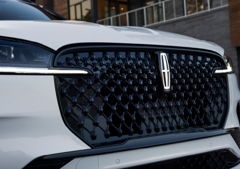 The black grille of a white 2025 Lincoln Aviator® SUV is shown with its fog lights on. | Uptown Lincoln in Wauwatosa WI