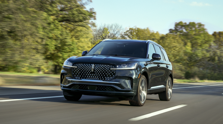 A 2025 Lincoln Black Label Aviator® SUV is being driven down a road lined with trees. | Uptown Lincoln in Wauwatosa WI
