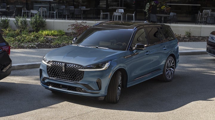 A Whisper Blue 2025 Lincoln Aviator® SUV is parked outside a modern building showcasing the driver’s side of the vehicle. | Uptown Lincoln in Wauwatosa WI