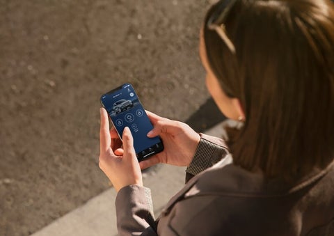 A person is shown interacting with a smartphone to connect to a Lincoln vehicle via the Lincoln Way® App. | Uptown Lincoln in Wauwatosa WI