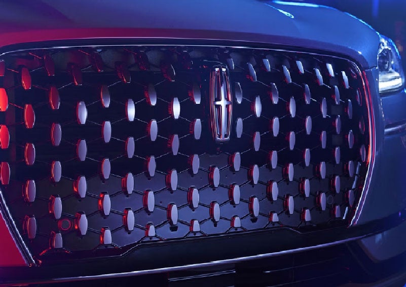 The grille of a 2025 Lincoln Corsair® SUV reflects neon light at night. | Uptown Lincoln in Wauwatosa WI