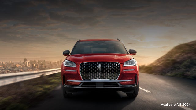 A 2025 red Lincoln Corsair® SUV is being driven down a road at sunset. | Uptown Lincoln in Wauwatosa WI
