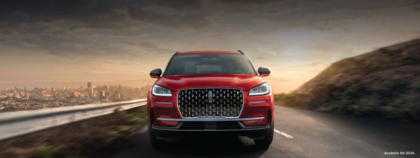 A 2025 red Lincoln Corsair® SUV is being driven down a road at sunset. | Uptown Lincoln in Wauwatosa WI