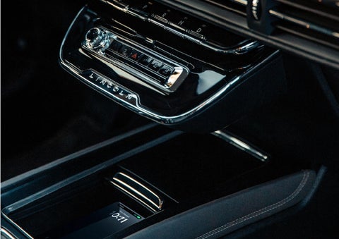 A smartphone is is being placed on the wireless charging pad in the front center console cubby. | Uptown Lincoln in Wauwatosa WI