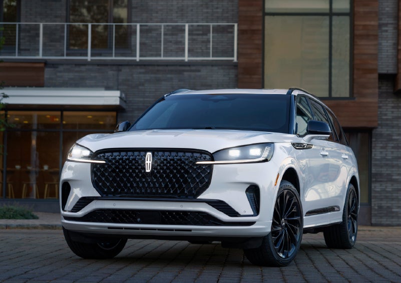 A 2026 Lincoln Aviator® Reserve model is shown with the available Jet Appearance Package parked near a restaurant. | Uptown Lincoln in Wauwatosa WI
