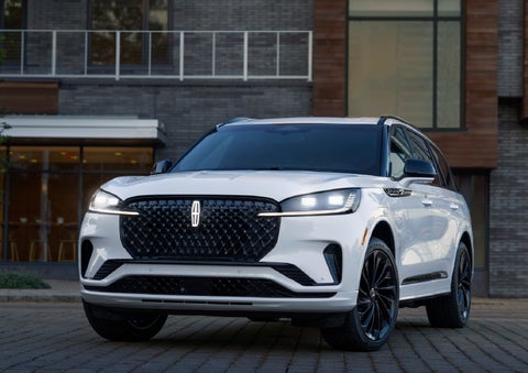 A 2026 Lincoln Aviator® Reserve model is shown with the available Jet Appearance Package parked near a restaurant. | Uptown Lincoln in Wauwatosa WI