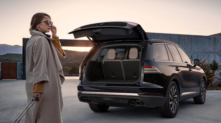 A woman approaches a 2026 Lincoln Aviator® SUV with its rear liftgate open. | Uptown Lincoln in Wauwatosa WI