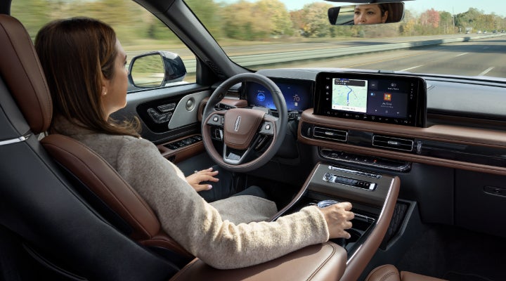 A 2026 Lincoln Aviator® SUV is being driven hands-free on a highway near a forest | Uptown Lincoln in Wauwatosa WI