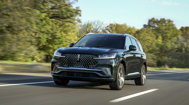 A 2026 Lincoln Black Label™ Aviator® SUV is being driven down a road lined with trees. | Uptown Lincoln in Wauwatosa WI