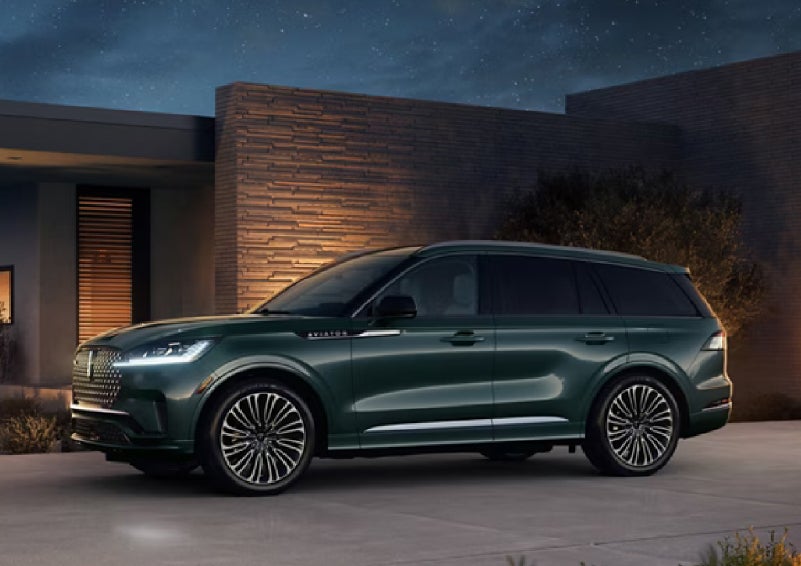 A green 2027 Lincoln Aviator® SUV is parked outside a contemporary home. | Uptown Lincoln in Wauwatosa WI