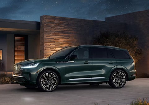 A green 2027 Lincoln Aviator® SUV is parked outside a contemporary home. | Uptown Lincoln in Wauwatosa WI