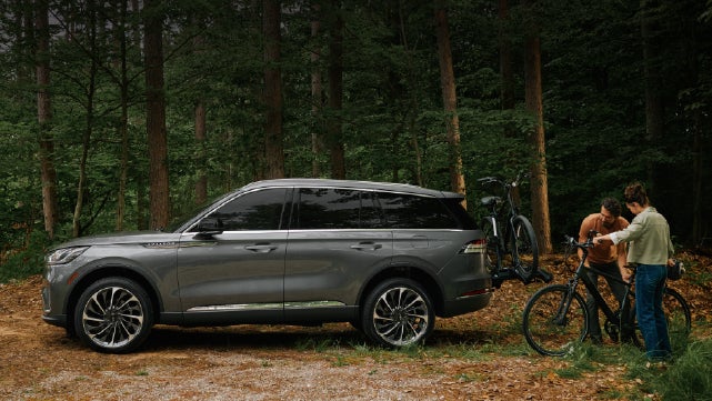 A father and son load e-bikes on a bike rack attached to a 2027 Lincoln Aviator® SUV. | Uptown Lincoln in Wauwatosa WI