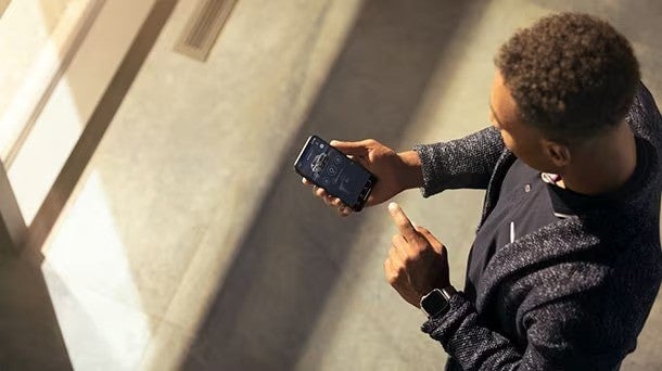 Man using a smartphone with a car control app, seen from above.