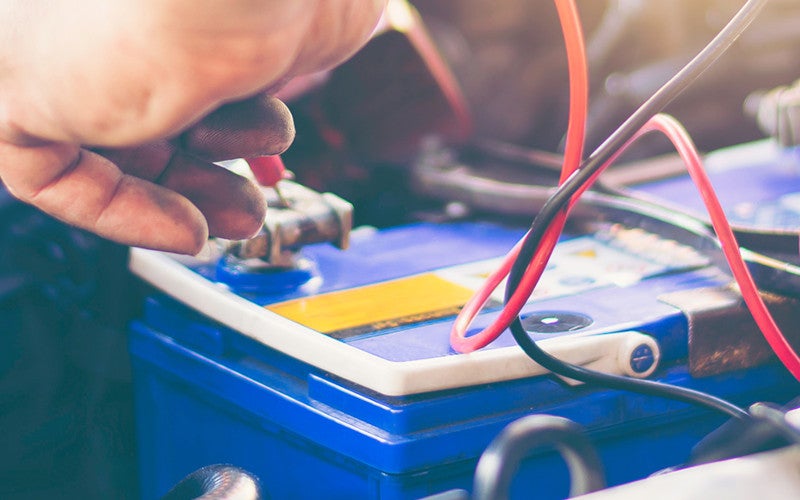 Close-up of a vehicle battery with testing cables attached during battery inspection, charging, or maintenance service